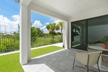 A patio with two chairs and a table and a lawn